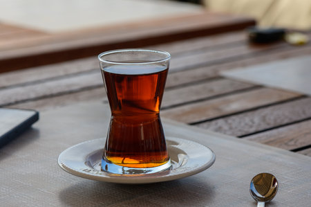 The sunlight gently illuminates a glass of herbal tea placed on a stylish saucer, inviting...