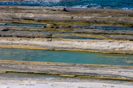 Exposed tidal pools in vibrant shades reflect sunlight while revealing fascinating geological...