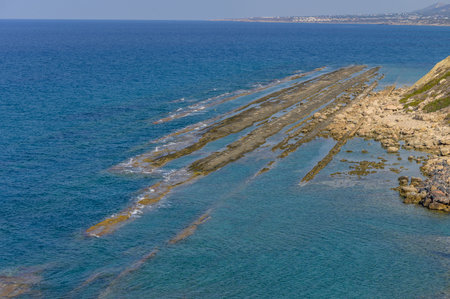 At midday, tranquil waves gently lap against striking rocky formations, creating a mesmerizing view of nature\'s beauty by the coastline, inviting exploration and reflection.の写真素材