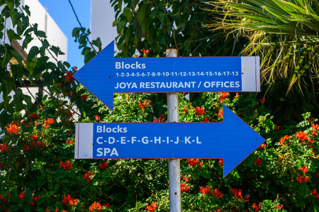 A vivid signpost directs visitors to a restaurant and spa, framed by lush greenery and blooming flowers.の写真素材