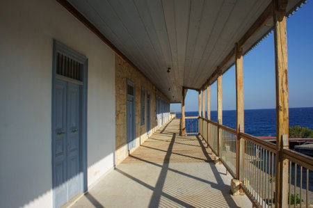Brightly lit corridor features blue doors and a stunning view of the ocean on a clear day.の写真素材