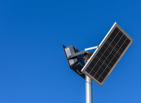 A solar panel mounts seamlessly beside an energy-efficient light, illuminating the surroundings under the sun.の写真素材