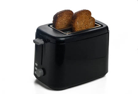 Freshly toasted slices of bread peek from a stylish black toaster, radiating warmth in a cozy kitchen environment.の写真素材