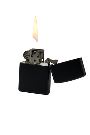 A striking black lighter stands open as a warm flame flickers, casting soft light in an intimate evening setting.の写真素材