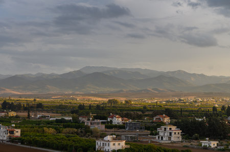 Fields of greenery stretch toward majestic mountains as dusk approaches, painting a serene landscape rich in nature.の写真素材