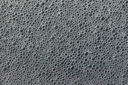 Close-up view of tiny bubbles capturing light, showcasing a unique pattern formed by air and liquid...