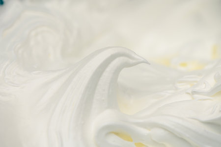 Soft, fluffy peaks of whipped cream rise, ready to enhance cakes, coffee, and sweet treats with their texture.の写真素材