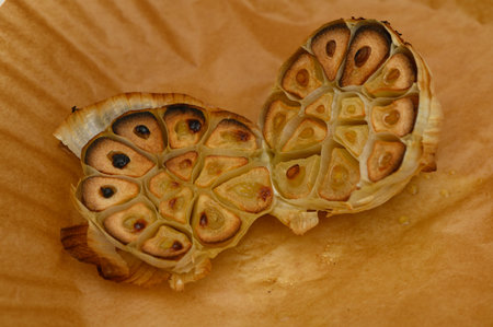 A softly roasted garlic bulb reveals its golden interior and unique shapes, showing true culinary artistry.の写真素材