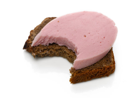 Bread with a creamy pink spread shows a bite taken out, inviting indulgence in a simple yet delightful treat.の写真素材
