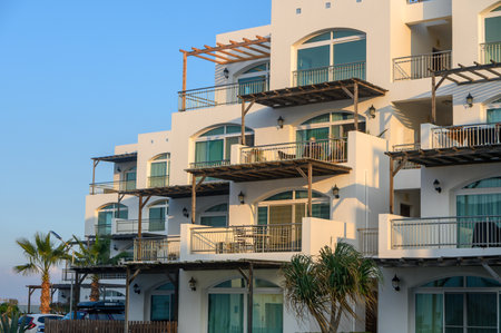 Stylish building features balconies with ocean views, framed by palm trees and a clear blue sky.
