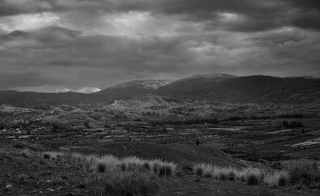 Dark clouds loom over rolling hills, creating a moody atmosphere in this tranquil, remote countryside.の写真素材