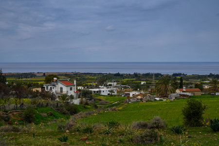 A picturesque coastal landscape showcases white houses amidst lush greenery and a calm ocean.