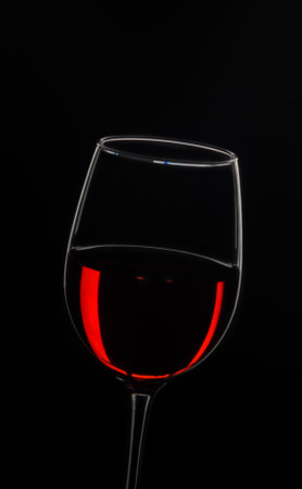 A sophisticated glass showcases deep red wine, reflecting light beautifully in contrast with a black backdrop.の写真素材