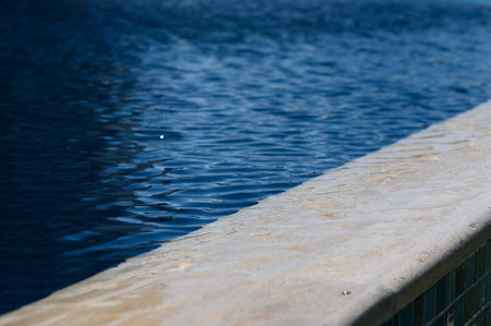 Soft ripples dance on the water's surface as sunlight warms the tranquil poolside, creating a peaceful atmosphere.の写真素材
