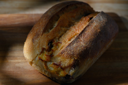 A golden crusted loaf shows caramelized edges, invitingly placed on a rustic wooden surface...