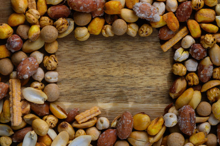 Vibrant collection of various nuts and snacks creates an inviting border on a rustic wooden...