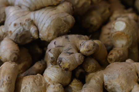 Crunchy, earthy ginger roots are stacked in abundance at a bustling market, inviting culinary...