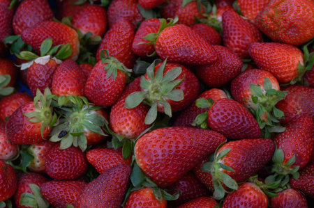 Baskets overflowing with lush, red strawberries create a delightful summer ambiance at the bustling...