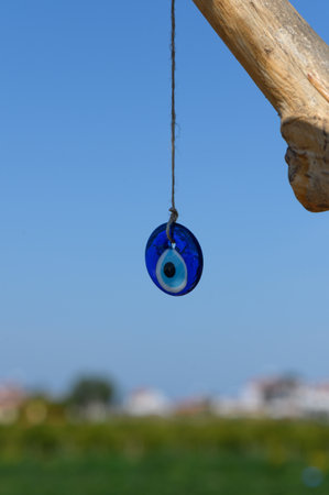 A vibrant blue talisman dangles gently from a weathered branch, catching the sunlight. The serene...
