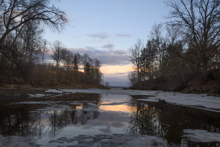 Serene twilight over a tranquil river reflecting the soft hues of dusk in early spring