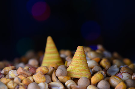 Brightly colored conical treats rest atop a bed of diverse nuts and seeds, creating a joyful...