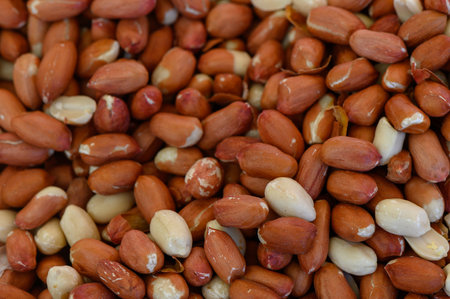 A close-up showcases a vibrant array of freshly harvested peanuts, their red-brown skins glistening...
