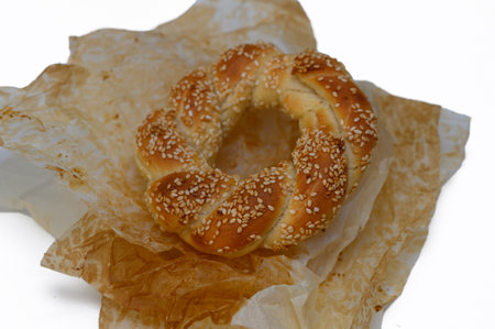 An artisanal bagel rests gracefully on crinkled parchment paper, exuding warmth and deliciousness....