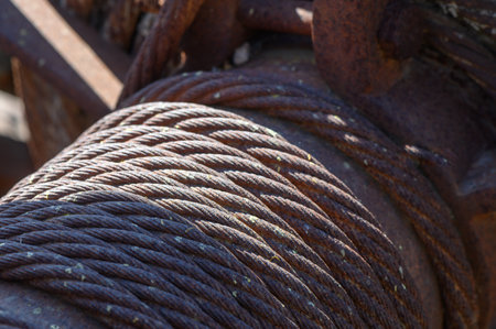 Twisted steel cables glisten under the bright sun, revealing traces of rust and wear. The heavy...