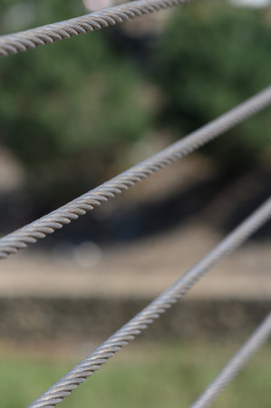 Amidst a peaceful outdoor setting, metal cables run horizontally, showing their strength.の写真素材