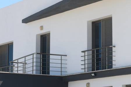 A striking view of a contemporary building showing sharp lines, elegant balconies, and a bright exterior under a clear blue sky. Urban elegance meets modern design elements.の写真素材