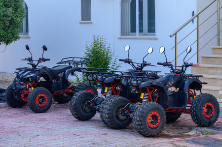 Three Black ATVs Parked Outdoors on Sunny Dayの写真素材