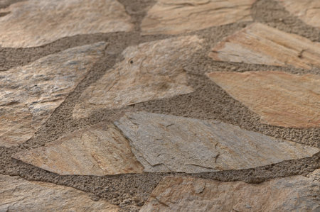 Close-up of natural stone tiles near a swimming pool. Rustic and warm surface ideal as background or...