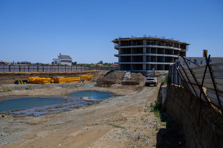 Excavator working near a foundation pit and partially built structure in Cyprus.の写真素材