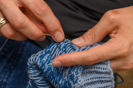 Hands of a woman knitting wool socks with a traditional pattern, cozy and detailed craftsmanship.