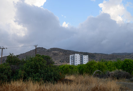 Traditional white house nestled at the base of a mountain in Cyprus, surrounded by Mediterranean landscape and blue sky.の写真素材