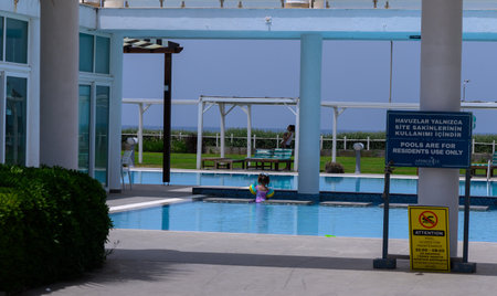 A joyful little girl enjoying a sunny day while swimming and splashing in a clean outdoor swimming pool. Summer fun and childhood happiness.の写真素材