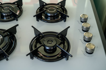 Modern gas stove shown in close-up on display in a household appliance store. Shiny metal finish...