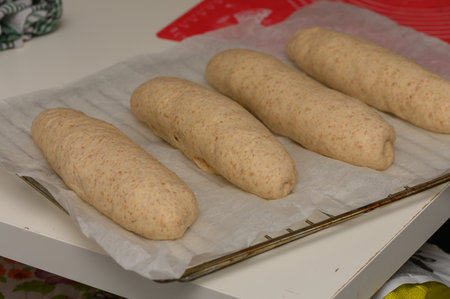 Close-up of homemade Graham bread loaves on a baking tray in a cozy kitchen setting.の写真素材