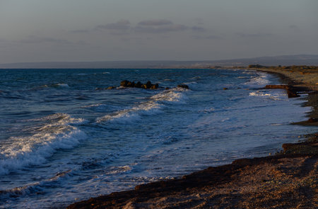 Golden sunset illuminates the calm waters of the Mediterranean Sea on the coast of Cyprusの写真素材