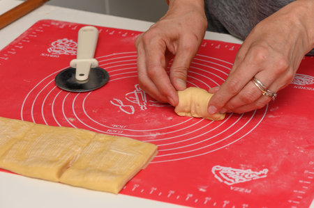 Woman Cutting Dough for Parker House Rolls in Kitchenの写真素材