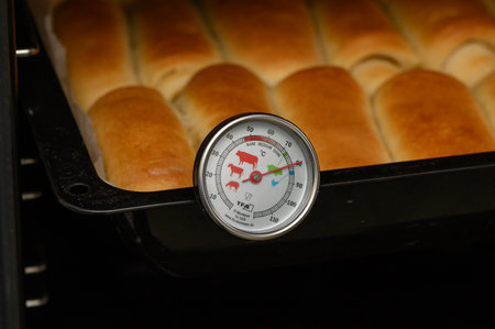 Golden homemade Parker House rolls baking in the oven. Soft, buttery, and freshly risen buns in a warm kitchen setting.の写真素材