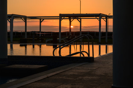 Beautiful sunset sky mirrored on the calm surface of a swimming pool, creating a serene and peaceful atmosphere.の写真素材