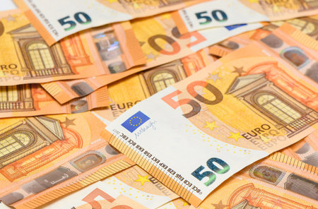 Multiple fifty euro banknotes randomly spread across a table surface, close-up background for financial and economic themes.の写真素材