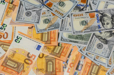 Scattered 100 US dollar and 50 euro banknotes lying on the table forming a money background, concept...