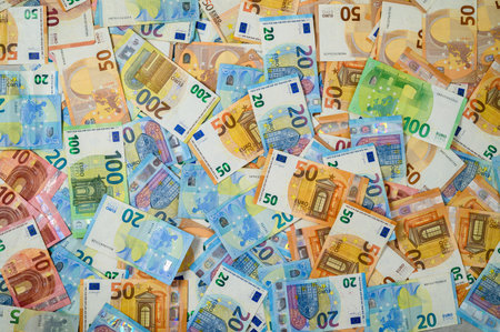 Many euro banknotes of 10, 20, 50, 100, and 200 denominations spread out as financial background, symbolizing wealth, economy, and European currency.の写真素材