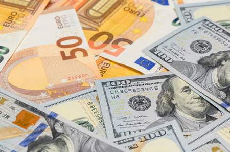 Scattered 100 US dollar bills and 50 euro banknotes forming financial background for forex, stock...