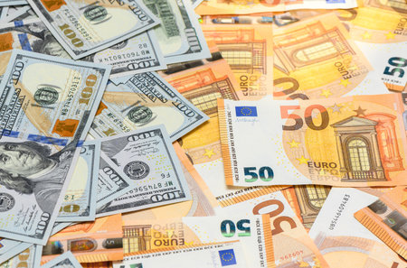 Scattered 100 US dollar bills and 50 euro banknotes as symbol of traditional money in contrast with...