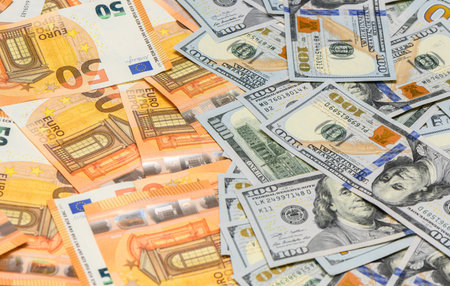Close-up of scattered hundred US dollar bills and fifty euro notes lying on a table, representing...
