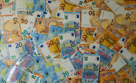 Euro banknotes in various denominations laid out on a white surface, ideal for money-related ads,...