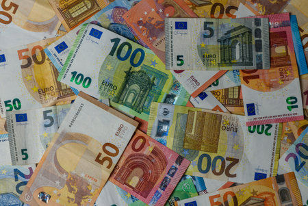 Assorted euro banknotes of different denominations create a dynamic financial background for...